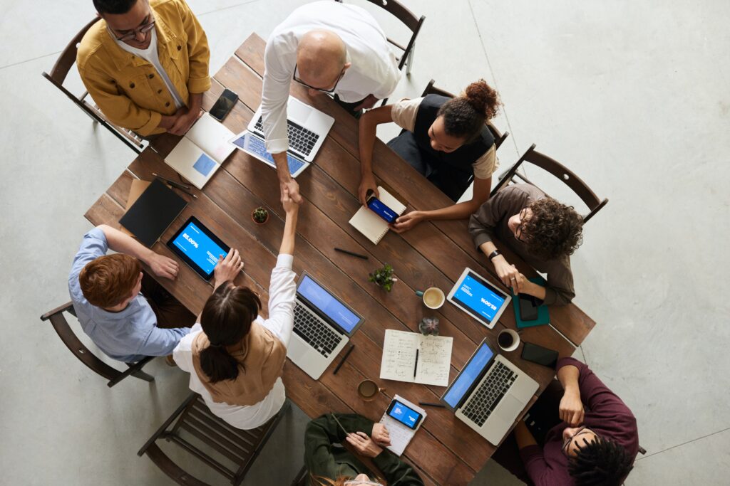 group of people sitting around a table with laptops