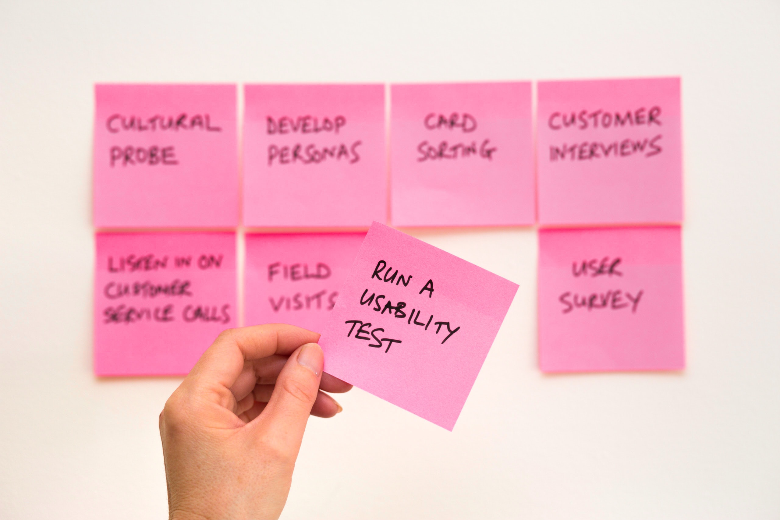 pink post it notes on a wall with text on