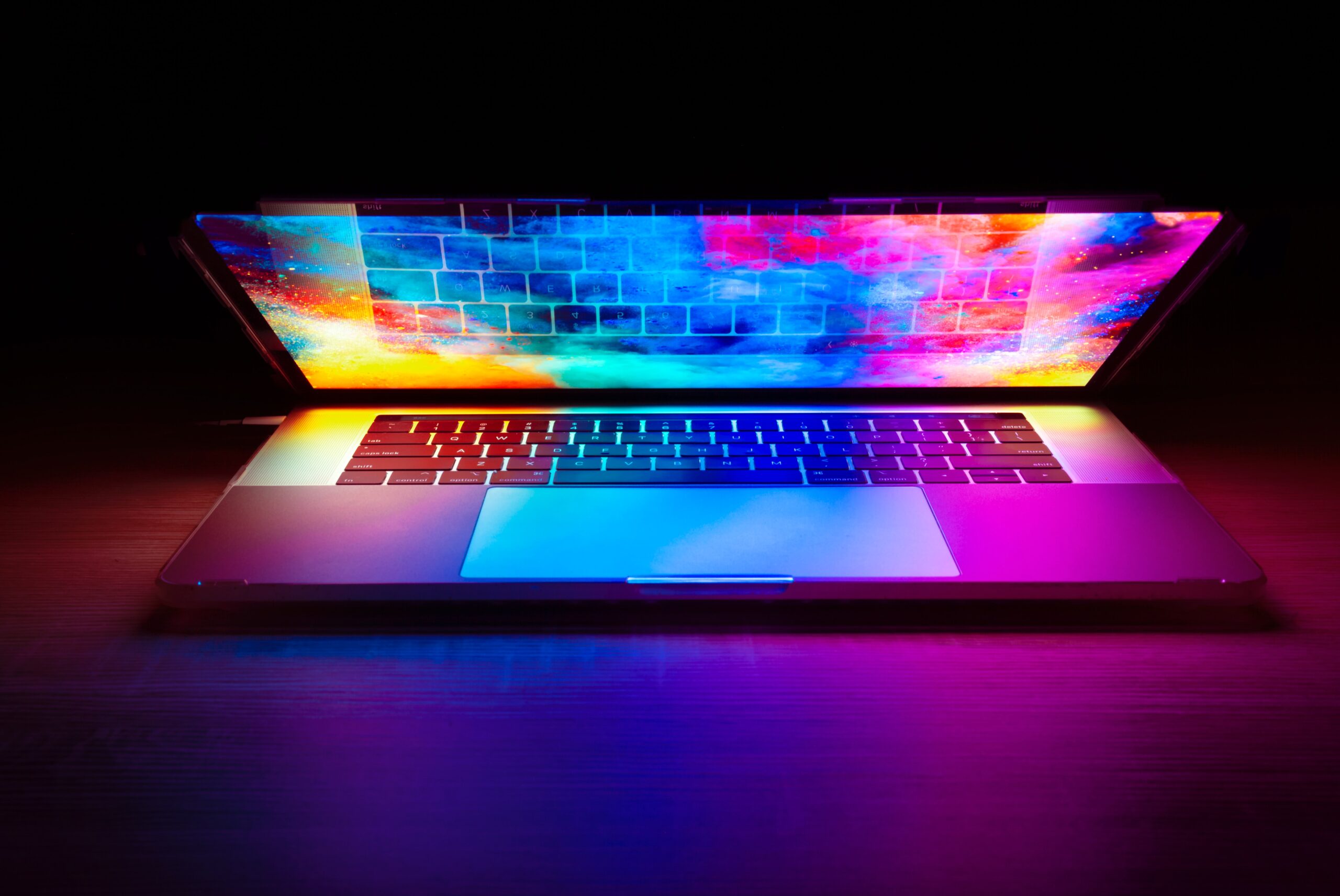 laptop half lcosed with a colourful screen against a dark background