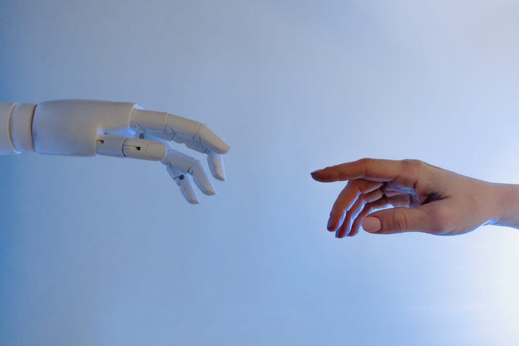 a robot hand reahcing out to a human hand on a blue background