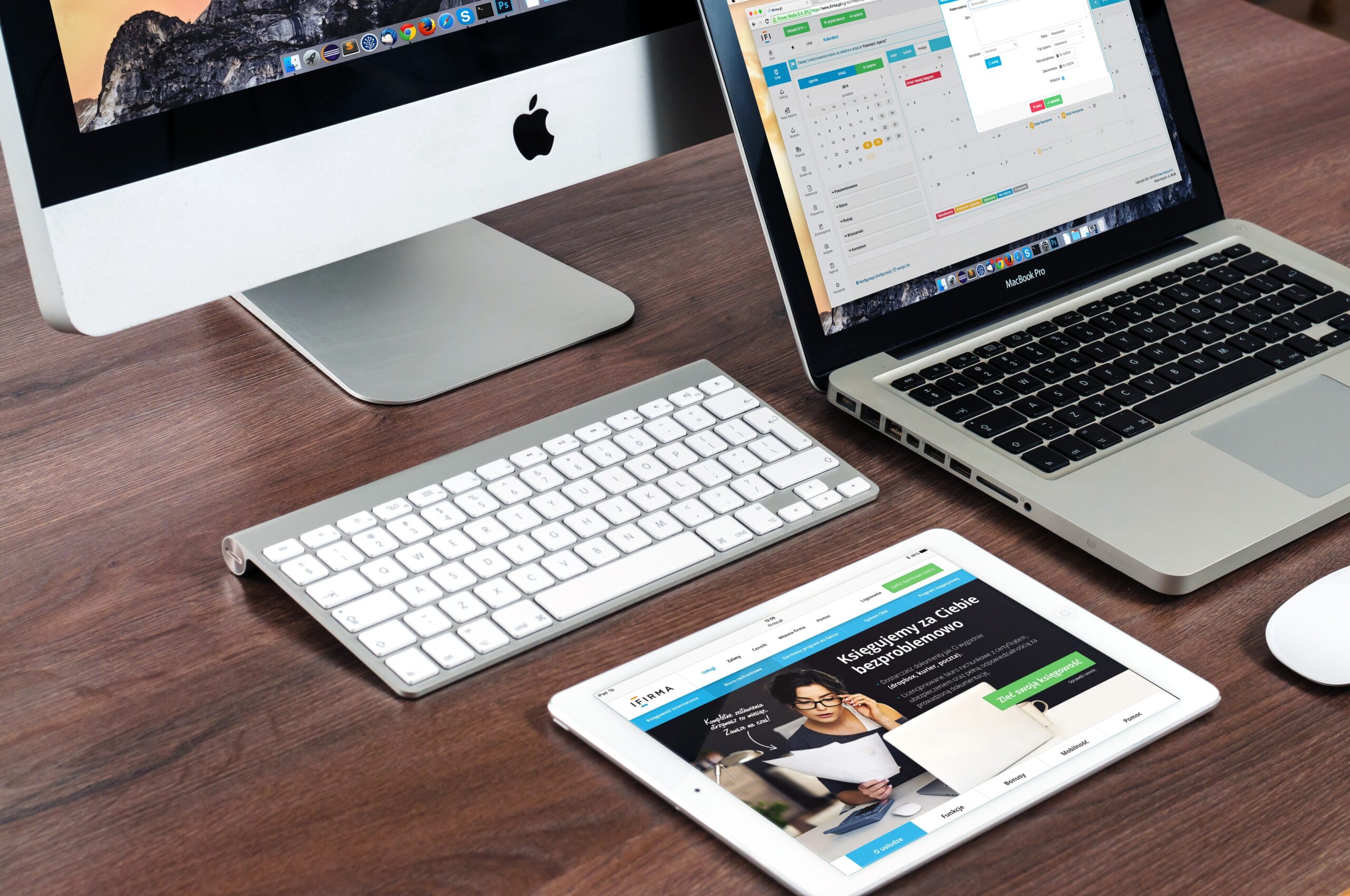 borwn desk with a macbook, mac and ipad