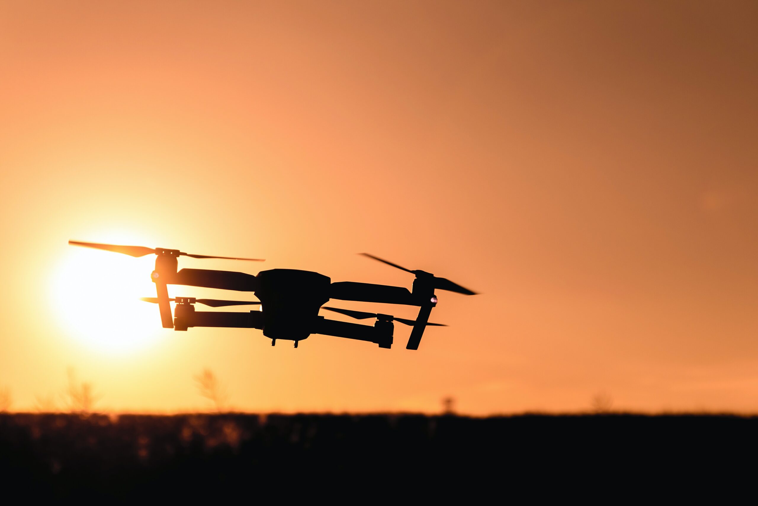 a flying drone against the orange sunset